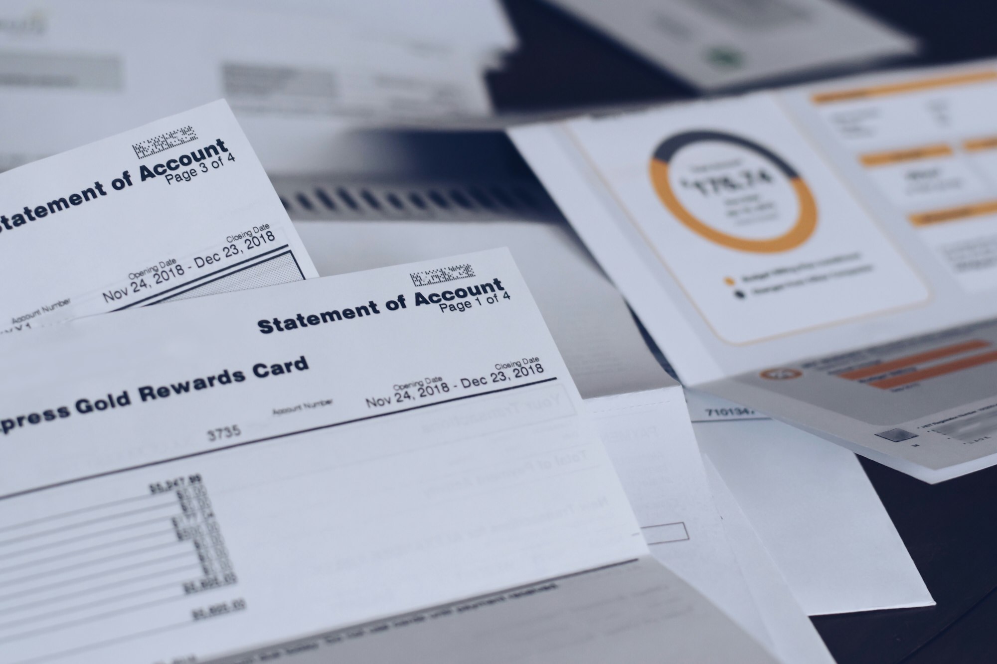 Scattered multiple utility bills and credit card statements on a desk.